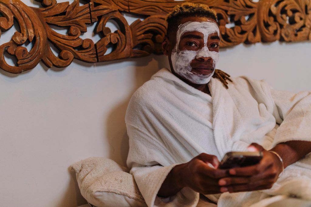 Man enjoying a relaxing spa day with a facial mask and robe, embracing self-care and relaxation.